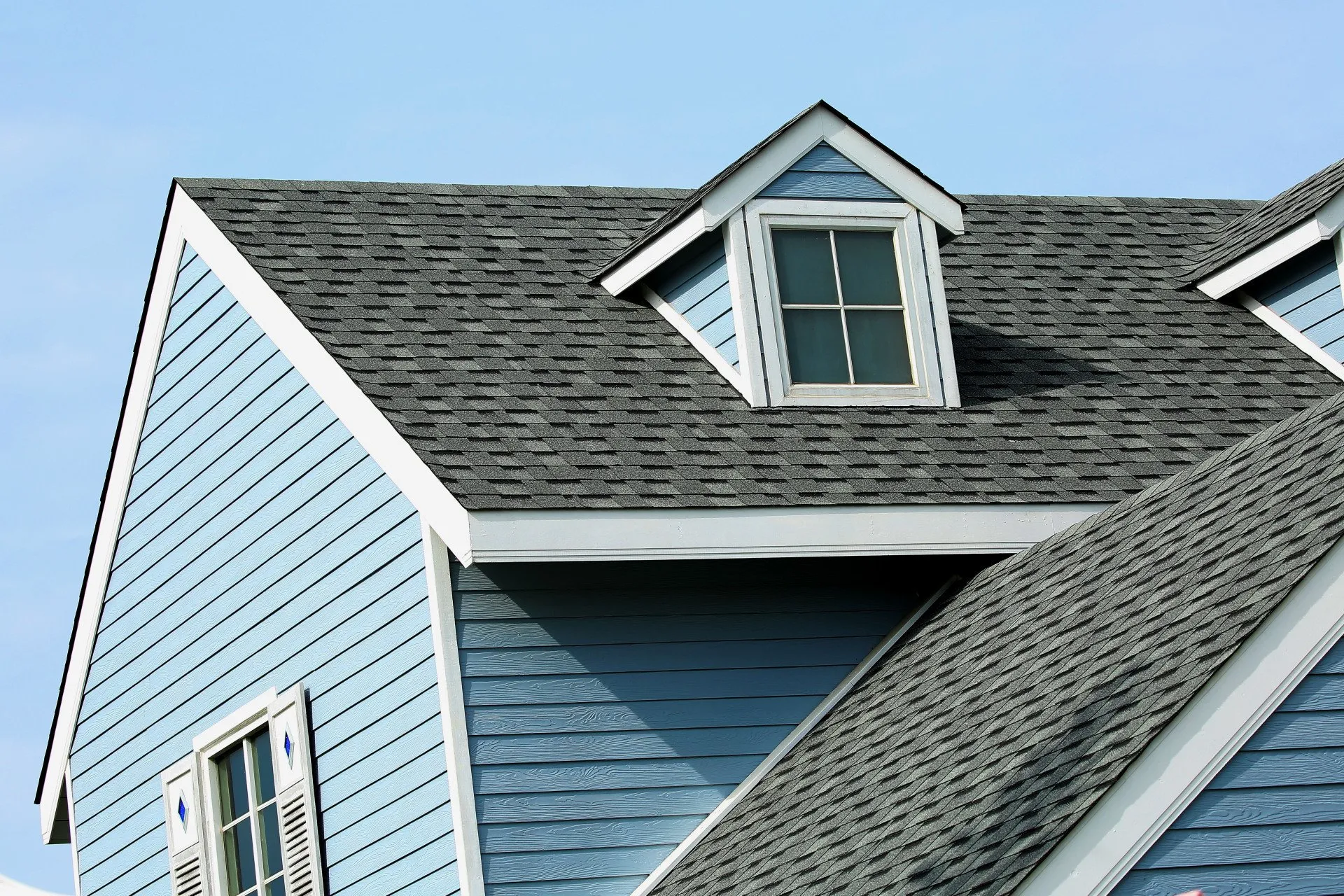 a blue house with a black roof and a white window